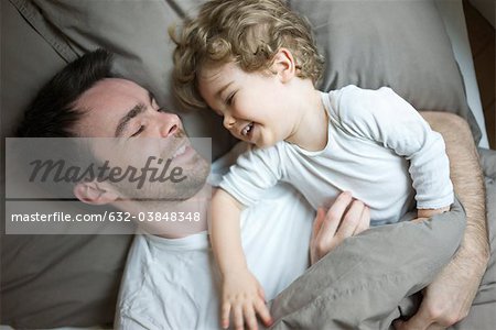 Father and young son relaxing together in bed, portrait