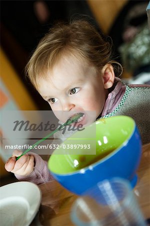 Toddler girl feeding herself with spoon