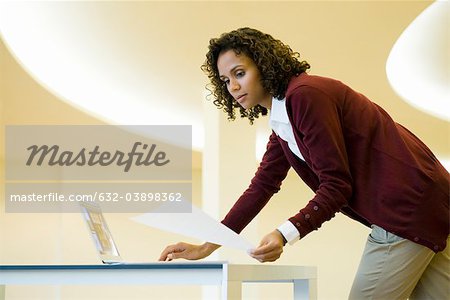 Businesswoman using laptop computer and looking at document