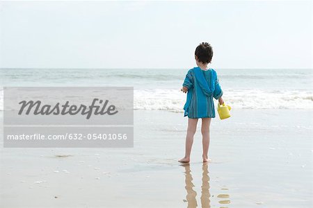 Boy standing on beach, looking at ocean