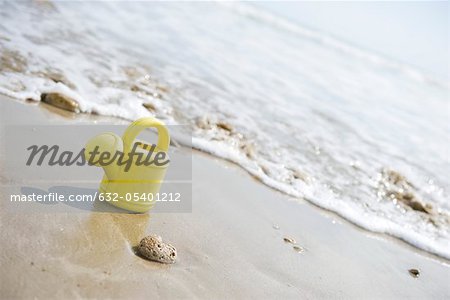 Toy watering can on beach