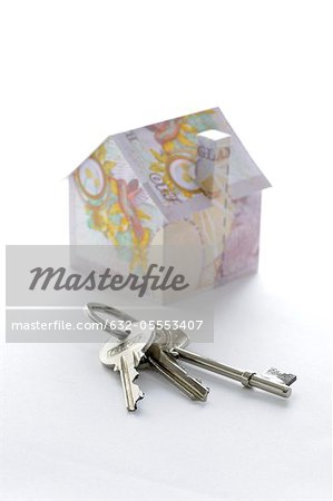 Bunch of keys and model house folded with British pound banknotes