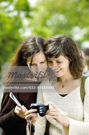 Woman showing digital camera to friend