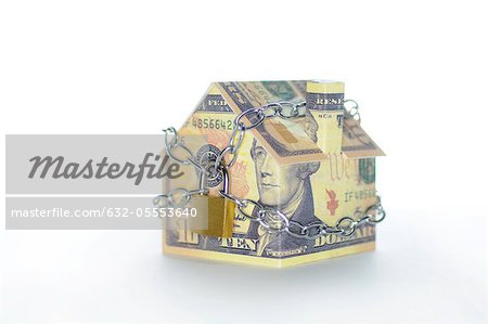Model house folded with dollar bills chained and padlocked