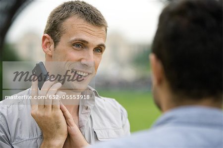 Man on phone call, covering cellphone mouthpiece with hand to talk to acquaintance