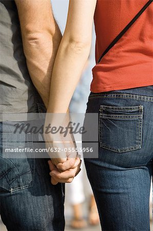 Couple holding hands, cropped rear view