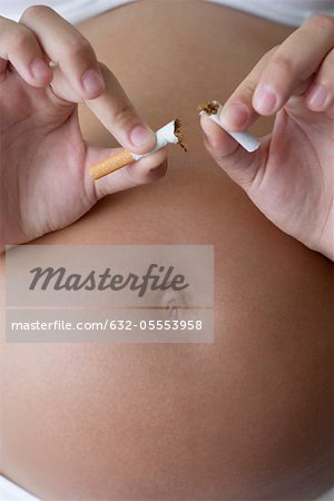Pregnant woman breaking cigarette in half, cropped