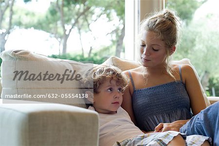 Mother and young son sitting together on sofa