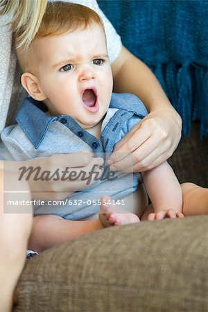 Baby yawning as mother dresses him