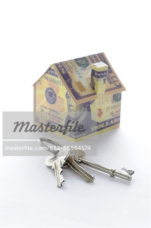 Bunch of keys and model house folded with dollar bills