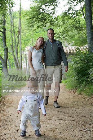 Toddler girl walking in woods with parents