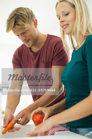 Couple washing vegetables together in kitchen