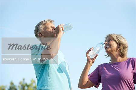 Senior couple drinking bottled water outdoors