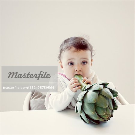 Infant biting fresh artichoke