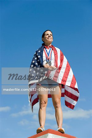 Female athlete being honored on podium, wrapped in American flag