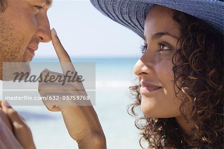 Couple at the beach, woman touching man's nose