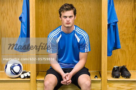 Young soccer player sitting in locker room, portrait