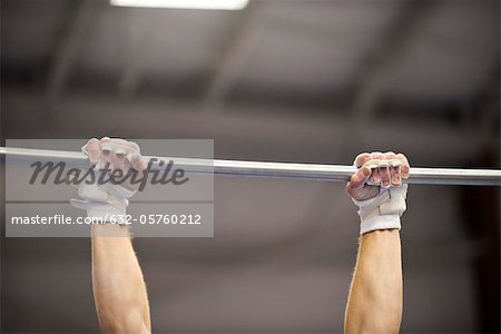 Gymnast gripping horizontal bar, cropped