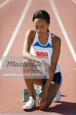 Female runner crouching at starting line with eyes closed