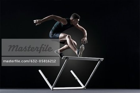 Male athlete clearing hurdle