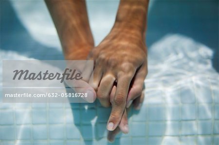 Couple holding hands underwater, cropped