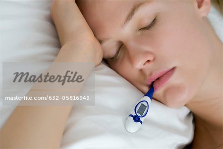 Young woman checking temperature with thermometer