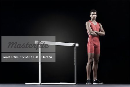 Male athlete standing by hurdle