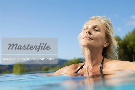 Mature woman relaxing in pool with eyes closed