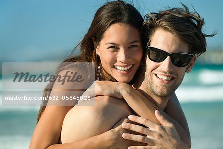 Happy young couple embracing at beach, portrait