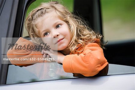 Little girl leaning out of car window, daydreaming, portrait