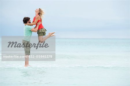 Couple at the beach, man lifting woman in air