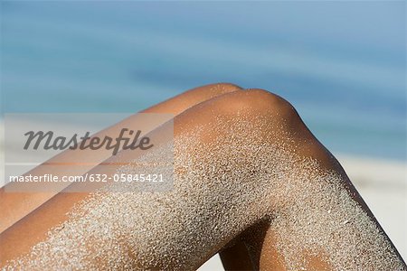 Woman's legs coated in sand at the beach