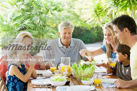 Multi-generation family having breakfast together outdoors