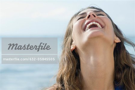Young woman laughing outdoors with head back and eyes closed