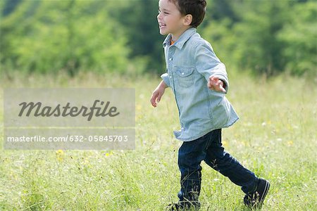 Little boy running in meadow, side view