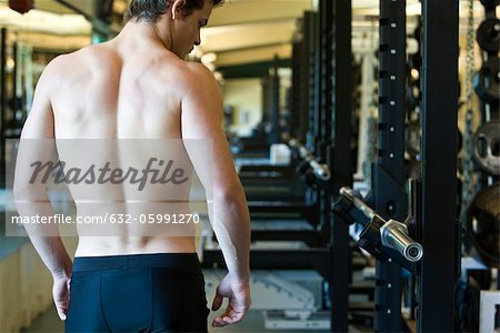 Barechested man in weight room, rear view