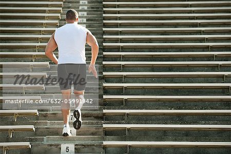 Man running up steps in stadium, rear view