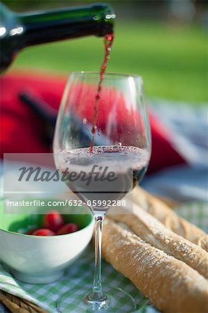 Pouring red wine at picnic