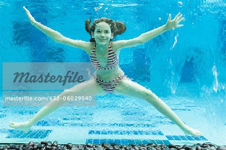 Girl swimming underwater in swimming pool