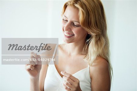 Young woman looking at pregnancy test, smiling