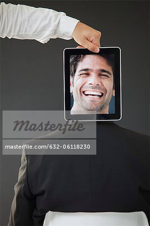 Man concealed behind digital tablet displaying image of laughing man, rear view