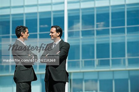 Business executives standing in front of office building talking