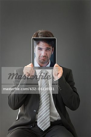 Man holding frowning photograph in front of his face