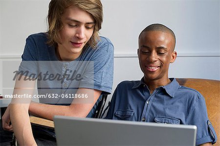 Young men using laptop computer together