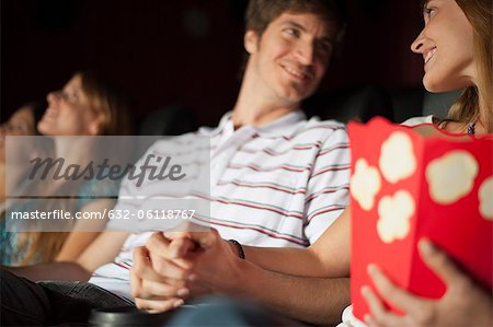 Couple looking at each other and holding hands in movie theater