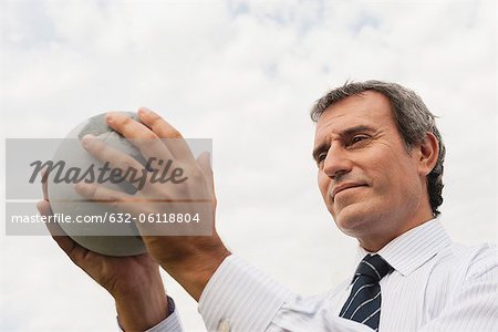 Businessman holding stone globe