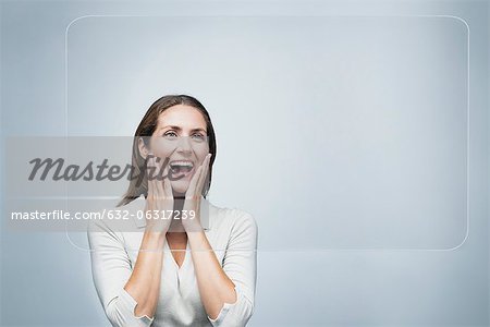 Woman looking at large transparent touch screen with surprised expression on face