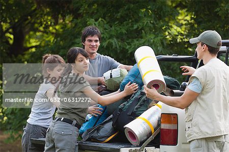 Young campers loading camping gear onto back of pick-up truck