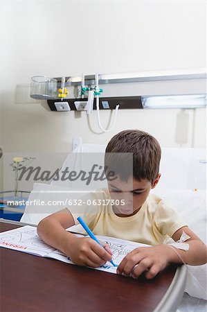 Boy coloring in hospital bed