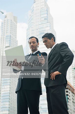 Business executives using laptop computer outdoors